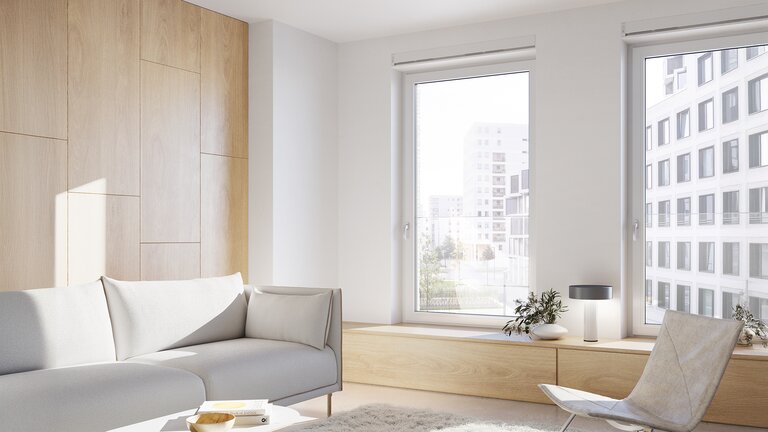 Ein Warteraum mit Couch und Sessel und Fenster mit Blick auf eine Stadt.